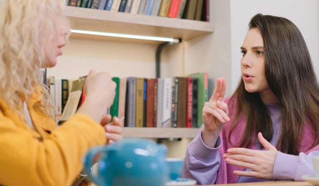 Two deaf students in library using British Sign Language 